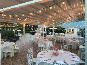 uma recepção de casamento com mesas brancas, cadeiras e luzes em villalessandra em Civitavecchia