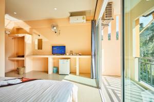 a bedroom with a bed and a desk and a window at Coco Palm Hotel Koh tao in Ko Tao