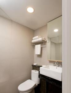 uma casa de banho com um WC, um lavatório e um espelho. em Hotel Santika Mega City Bekasi em Bekasi