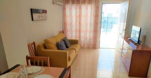 uma sala de estar com um sofá amarelo e uma mesa em ACV - Marina Trebol I-2ª linea, planta baja, sur em Oropesa del Mar