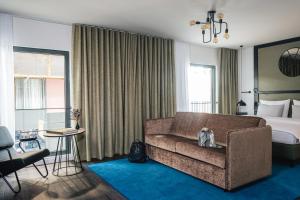ein Hotelzimmer mit einem Sofa und einem Bett in der Unterkunft AMERON München Motorworld in München