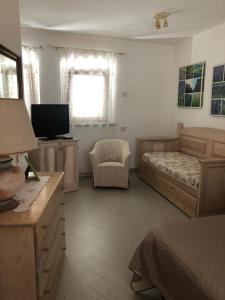 una camera con letto, sedia e televisore di Casa Azzurra a Santa Teresa di Gallura