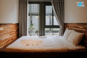 a bed in a room with a large window at Amacon Hotel & Coffee in Buôn Kô Sir