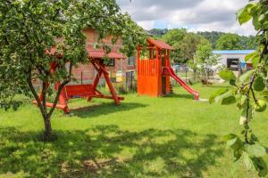 a playground with a red swing set in a yard at Apartamente Gergely Apartmanok in Praid