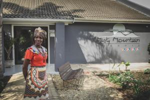 an older woman standing in front of a building at Misty Mountain Reserve in Stormsrivier