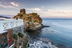 a person standing on a cliff overlooking the ocean at Castel Abaso Boutique Apartments by Explore Andros in Andros