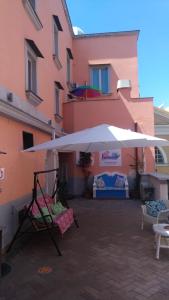 duży biały parasol przed różowym budynkiem w obiekcie Il Borghetto Apartments & Rooms w mieście Procida