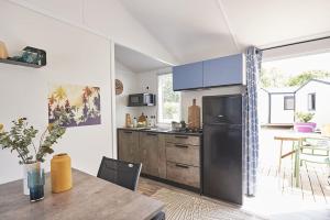 uma cozinha com um frigorífico de aço inoxidável e uma mesa em Camping Paradis le Rocher de la Granelle em Le Bugue