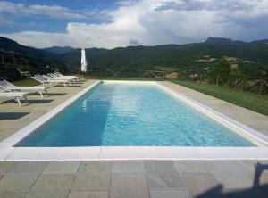 - une piscine avec des chaises et une vue sur les montagnes dans l'établissement Antico Casale di Ferdinandi, à Bibbiena