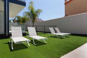 a row of white chairs sitting on top of grass at Residence Meridian Unità 2 in Villa San Pietro
