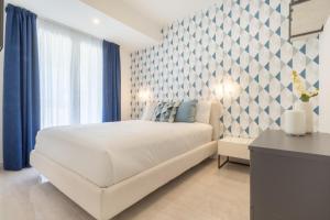 Schlafzimmer mit einem weißen Bett und blauen Vorhängen in der Unterkunft Residence Meridian Unità 4 in Villa San Pietro