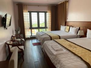 um quarto de hotel com duas camas e uma televisão em Hotel Ngoc Anh - Van Don em Quang Ninh