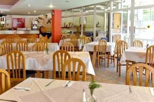 a restaurant with white tables and chairs and a kitchen at Hotel Oasis in Albena
