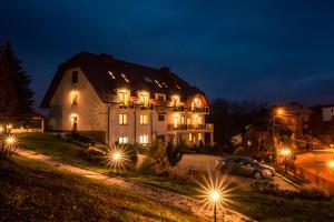 ein großes weißes Haus in der Nacht mit Lichtern in der Unterkunft Hotel Kasztelan in Dobczyce