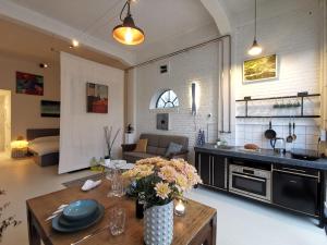 eine Küche und ein Wohnzimmer mit einem Tisch mit Blumen darauf in der Unterkunft Studio Blank - a night in the gallery in Den Oever