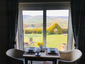 einen Tisch und Stühle vor einem großen Fenster in der Unterkunft Yorecroft in Aysgarth