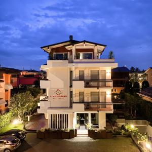 - un grand bâtiment blanc avec une voiture devant dans l'établissement Residence Il Melograno, à Sirmione