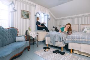 uma mulher sentada numa cama num quarto em Taulun Kartano em Kankainen