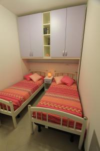 2 camas en una habitación pequeña con armarios blancos en Apartment SOLARIUM, en Bibione
