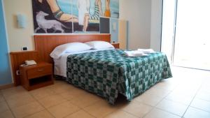 a bedroom with a bed with a green and white blanket at Hotel Royal in Giulianova