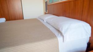 a bed with white sheets and a wooden wall at Hotel Royal in Giulianova