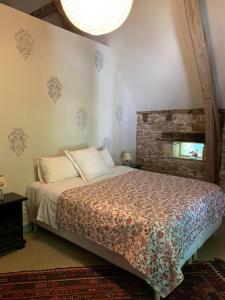 1 dormitorio con cama y pared de ladrillo en The Stables Gite at Chateau Mas de Pradié, en Foissac