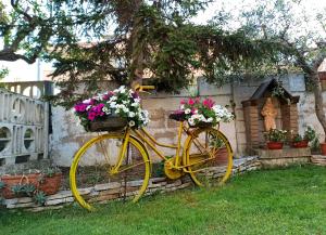 una bicicletta gialla con fiori in un cortile di Goccia Azzurra a Silvi Marina