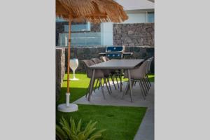 un patio con tavolo, sedie e prato di Luxury Villa - new building with panoramic sea view ad Adeje