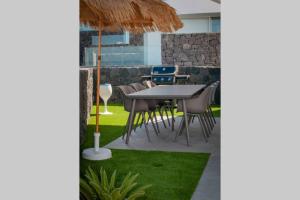 un patio con mesa, sillas y césped en Luxury Villa - new building with panoramic sea view, en Adeje