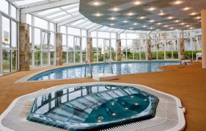 een groot binnenzwembad in een gebouw met ramen bij Laguna Beach Hotel in Albena