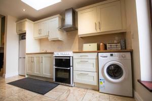 a kitchen with white cabinets and a washer and dryer at Derry City Private Apartment in Culmore