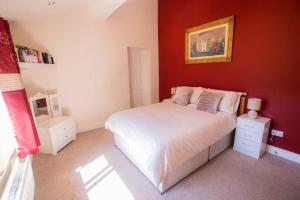 a bedroom with a white bed and a red wall at Derry City Private Apartment in Culmore