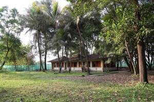 a house in the middle of a field with trees at Pinewood Resort in Karjat
