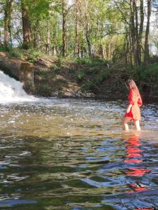 una chica parada en el agua en un río en La Maison entièrement équipée - Boulangerie, en Saint-Pierre-les-Étieux