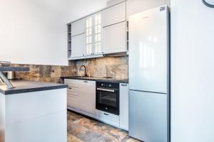 a kitchen with white cabinets and a refrigerator at INPOINT CRACOW Mogilska Tower Apartments near Tauron Arena in Krakow