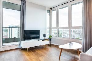 a living room with a tv and large windows at INPOINT CRACOW Mogilska Tower Apartments near Tauron Arena in Krakow
