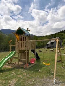 a wooden playground with a slide and a swing at Les chalets de la forêt d'Issaux in Osse-en-Aspe