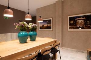two blue vases with flowers on a wooden table at Goodnight Cádiz Apartments in Cádiz