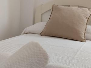 a white bed with a pillow on top of it at Apartamentos Bolonia - M a n u e l a in Bolonia