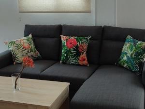 a black couch with pillows and a coffee table at Apartamentos Bolonia - M a n u e l a in Bolonia