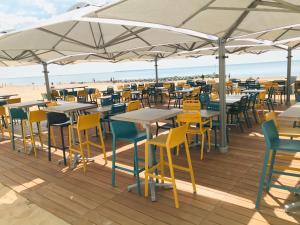 a group of tables and chairs under umbrellas on a beach at Hôtel Restaurant L'Atelier des Cousins in Châtelaillon-Plage