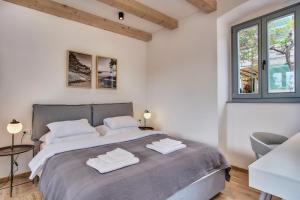 a white bedroom with a large bed and two windows at Casa Santa Maria Vacation House in Mali Lošinj