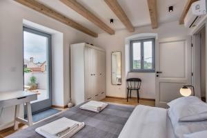 a bedroom with a bed and a desk and a window at Casa Santa Maria Vacation House in Mali Lošinj