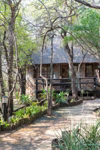a house with a fence and trees in front of it at Blyde River Canyon Lodge in Hoedspruit