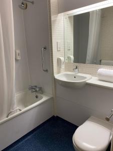 y baño con lavabo, aseo y espejo. en ibis budget Dundee Camperdown en Dundee