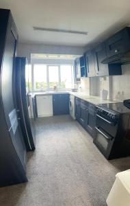 una pequeña cocina con armarios azules y una ventana en Large 4 bedroom home in Boston Spa village In-between York, Harrogate and Leeds, Sleeps 9, en Boston Spa