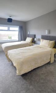 2 camas en un dormitorio con ventana en Large 4 bedroom home in Boston Spa village In-between York, Harrogate and Leeds, Sleeps 9 en Boston Spa