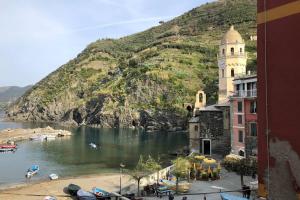 a building with a clock tower next to a body of water at La Gianchina di Vernazza - Central Cozy Apt Wi-Fi in Vernazza
