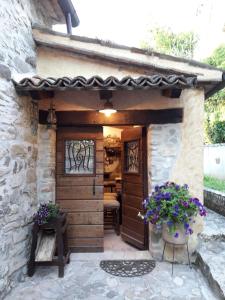 a stone house with a wooden door and flowers at Mulino Sandaci - Casa Vacanze in Montefotogno
