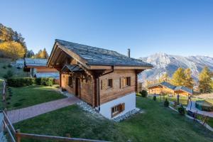 a small wooden house on a lawn with mountains in the background at Chalet Asphodel in Plan Fey